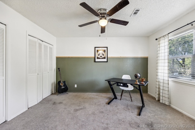 carpeted home office with ceiling fan and a textured ceiling