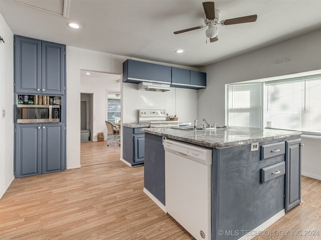 kitchen featuring light hardwood / wood-style floors, sink, an island with sink, white appliances, and blue cabinetry