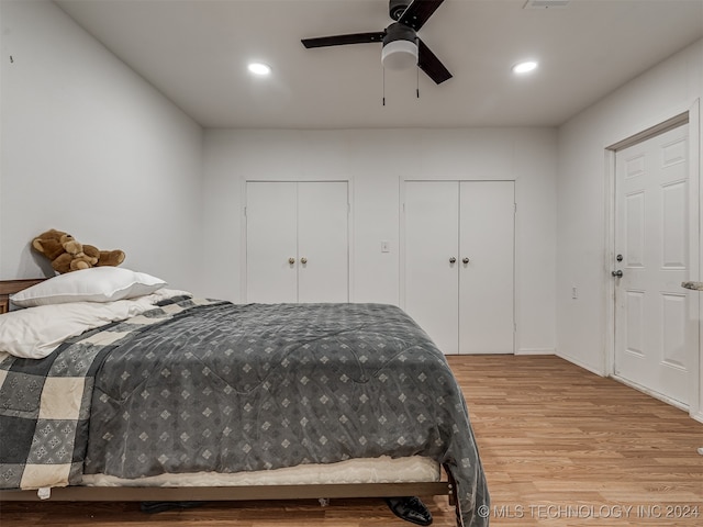 bedroom featuring light wood-type flooring, two closets, and ceiling fan