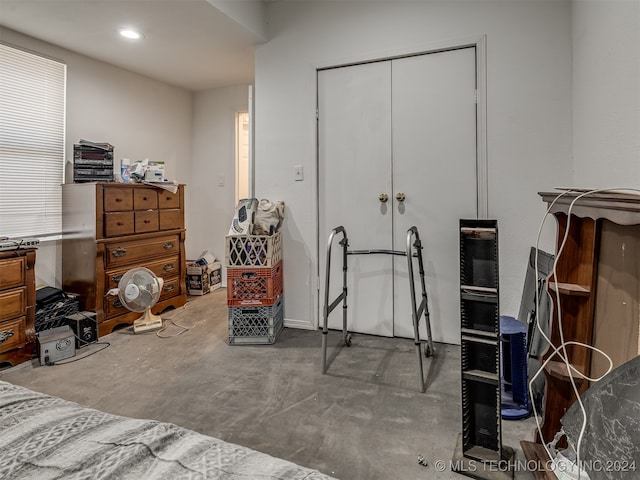 bedroom featuring multiple windows, concrete floors, and a closet