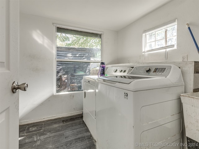 laundry area featuring dark wood-type flooring, washing machine and dryer, and a healthy amount of sunlight