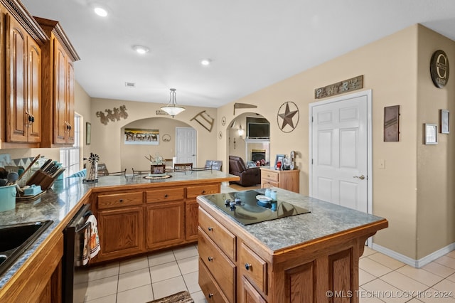 kitchen featuring light tile patterned flooring, lofted ceiling, a center island, decorative light fixtures, and stainless steel dishwasher