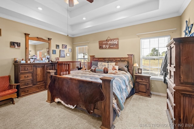 bedroom featuring ornamental molding, a tray ceiling, ceiling fan, and light colored carpet