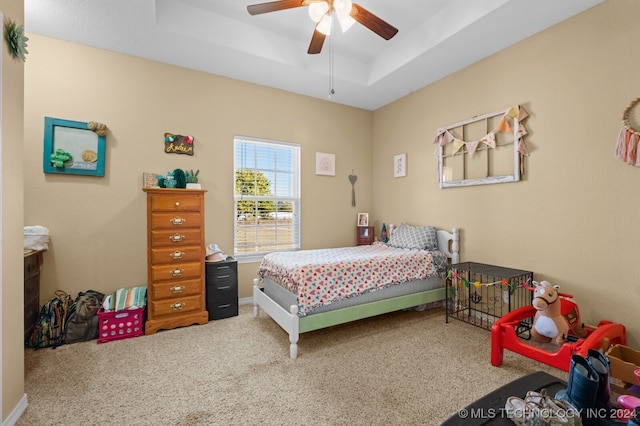 bedroom with ceiling fan, a raised ceiling, and carpet flooring