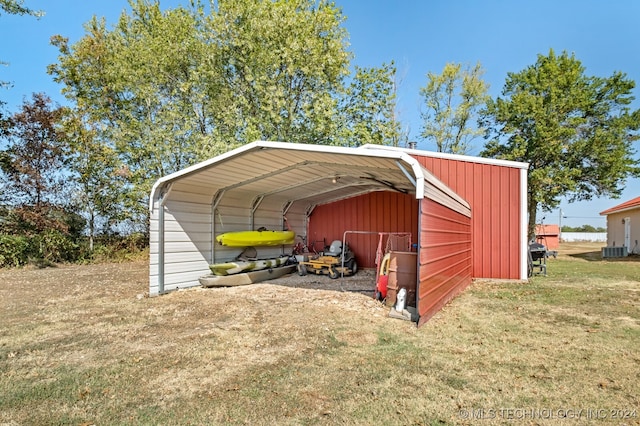 view of outdoor structure with central AC unit, a carport, and a yard