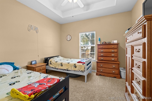 carpeted bedroom with ceiling fan and a raised ceiling