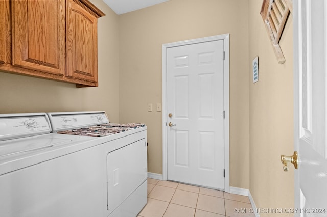 washroom with light tile patterned floors, cabinets, and washer and dryer