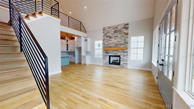 unfurnished living room with high vaulted ceiling, light hardwood / wood-style floors, and a fireplace