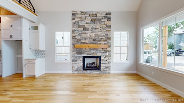 unfurnished living room with a fireplace, lofted ceiling, and light hardwood / wood-style flooring