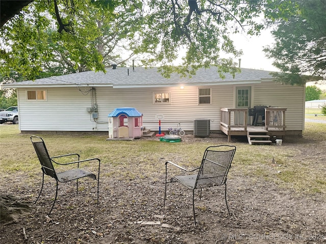 back of property with cooling unit, a deck, and a lawn