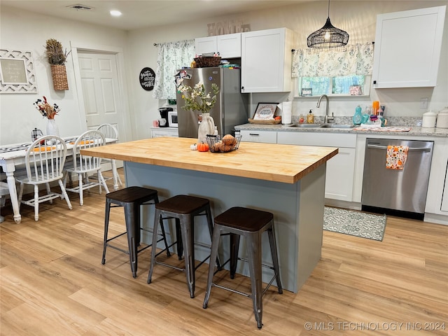 kitchen with stainless steel appliances, sink, wooden counters, and white cabinetry