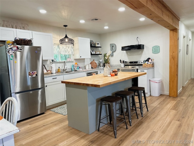 kitchen featuring butcher block countertops, white cabinets, appliances with stainless steel finishes, and a center island