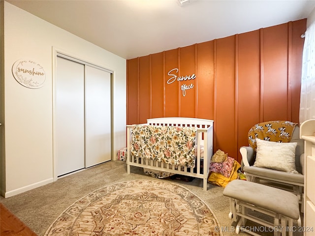 bedroom with a nursery area, a closet, and carpet flooring