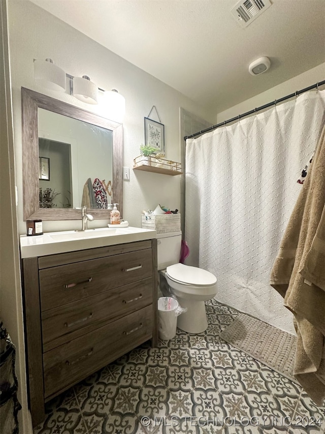 bathroom featuring vanity, walk in shower, a textured ceiling, tile patterned flooring, and toilet