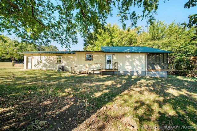 rear view of property featuring a yard and a sunroom