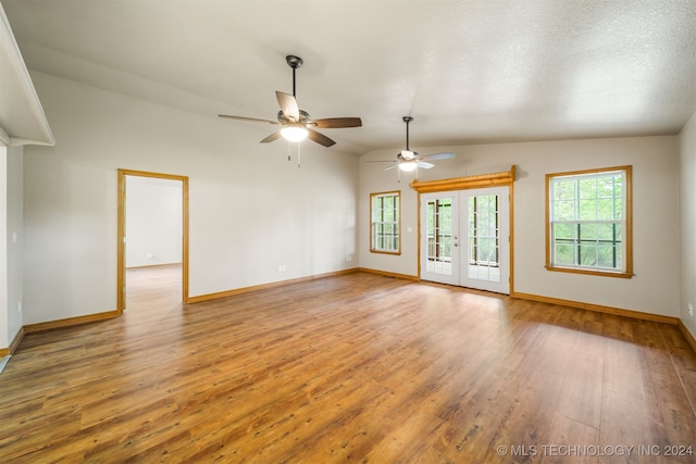 spare room with vaulted ceiling, a textured ceiling, ceiling fan, light hardwood / wood-style flooring, and french doors