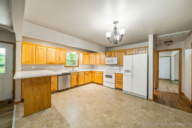 kitchen featuring a notable chandelier, a wealth of natural light, white appliances, and hanging light fixtures