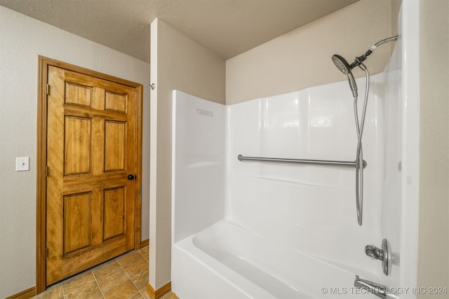 bathroom with a textured ceiling and bathtub / shower combination