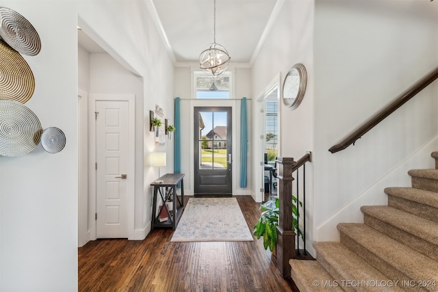 entrance foyer featuring ornamental molding, an inviting chandelier, and dark wood-type flooring