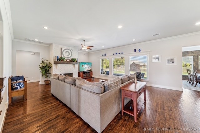 living room featuring a brick fireplace, ceiling fan, crown molding, and dark hardwood / wood-style flooring