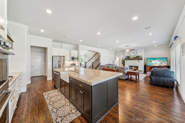 kitchen featuring a center island with sink, dark wood-type flooring, a large fireplace, dark brown cabinetry, and sink