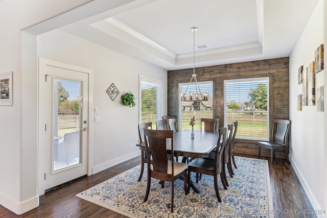 dining space featuring an inviting chandelier, a tray ceiling, and dark hardwood / wood-style flooring