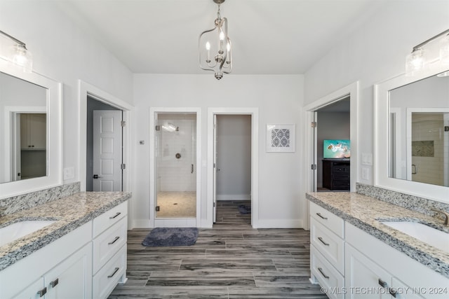 bathroom featuring hardwood / wood-style flooring, vanity, an inviting chandelier, and an enclosed shower