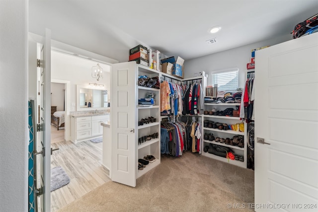 spacious closet with an inviting chandelier and light hardwood / wood-style floors