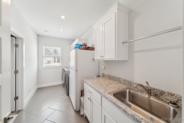 kitchen with white refrigerator, sink, white cabinetry, light tile patterned floors, and light stone countertops