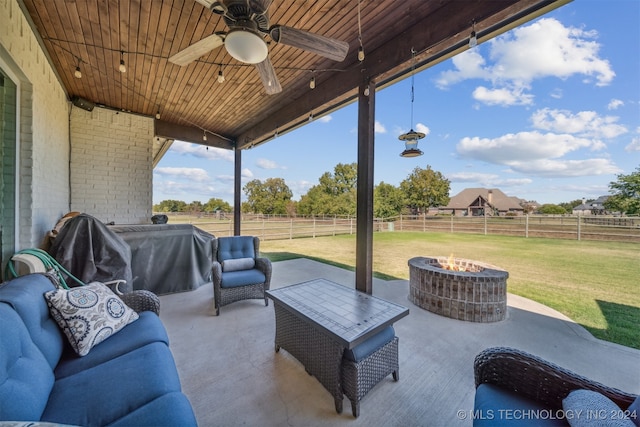 view of patio / terrace featuring area for grilling, an outdoor living space with a fire pit, ceiling fan, and a rural view