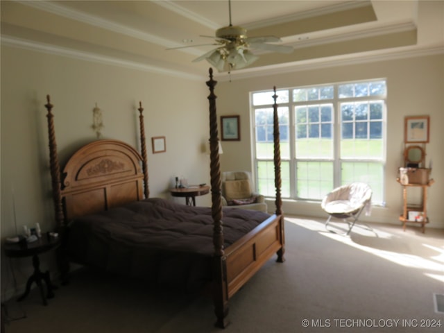 carpeted bedroom with ceiling fan, a tray ceiling, and crown molding