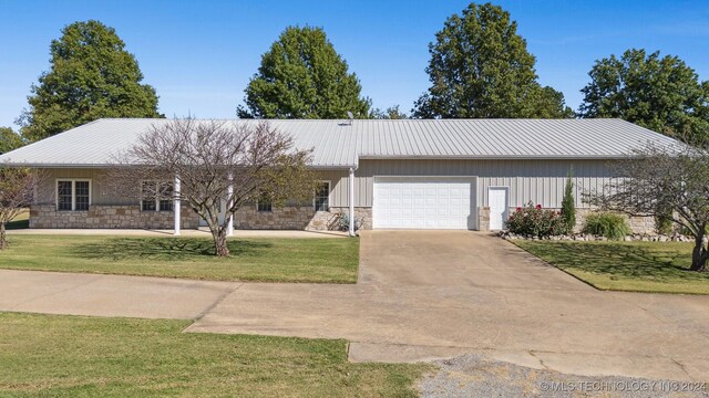 1202 SW 9th St, Wagoner, OK 74467 - single story home with an attached garage, metal roof, stone siding, and a front lawn
