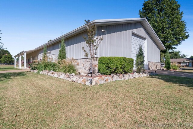 1202 SW 9th St, Wagoner, OK 74467 - view of side of property with a lawn, stone siding, and a detached garage