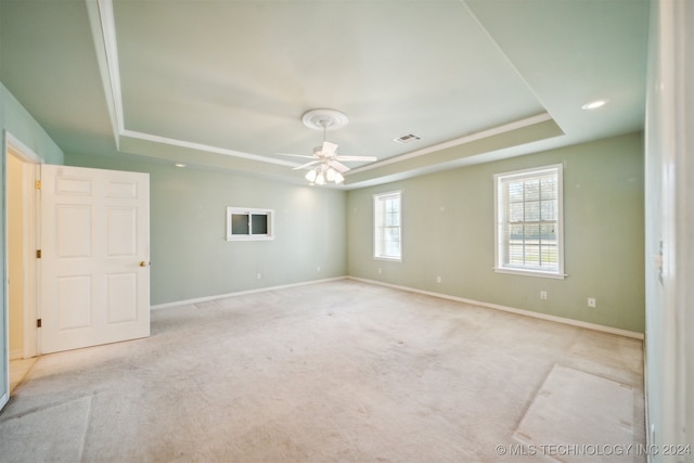 carpeted spare room with ceiling fan and a tray ceiling