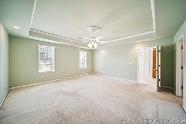 carpeted spare room featuring a tray ceiling and ceiling fan