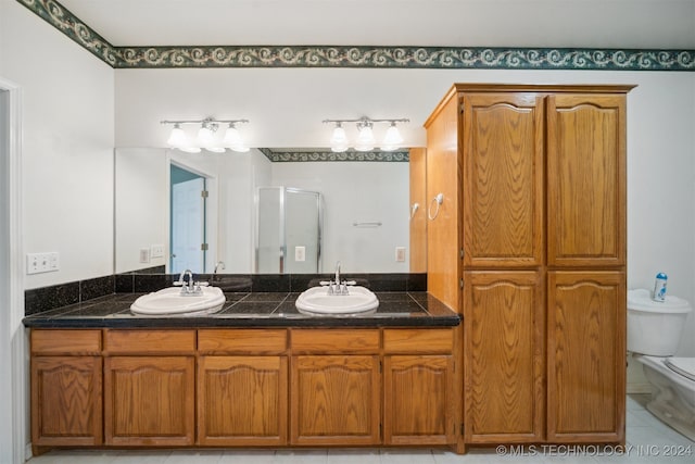 bathroom with vanity, toilet, a shower with door, and tile patterned floors