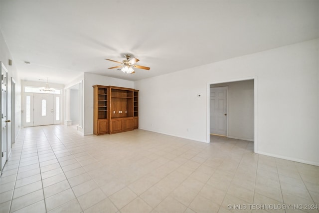 spare room featuring ceiling fan with notable chandelier and light tile patterned flooring