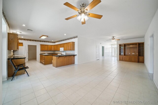 1202 SW 9th St, Wagoner, OK 74467 - kitchen featuring brown cabinetry, a ceiling fan, dark countertops, open floor plan, and recessed lighting