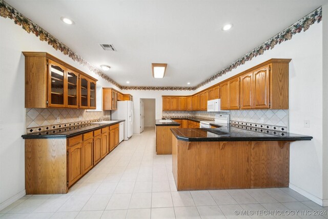 1202 SW 9th St, Wagoner, OK 74467 - kitchen featuring decorative backsplash, brown cabinetry, visible vents, a peninsula, and white appliances