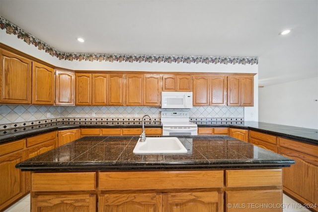 kitchen featuring a center island with sink, sink, white appliances, and decorative backsplash