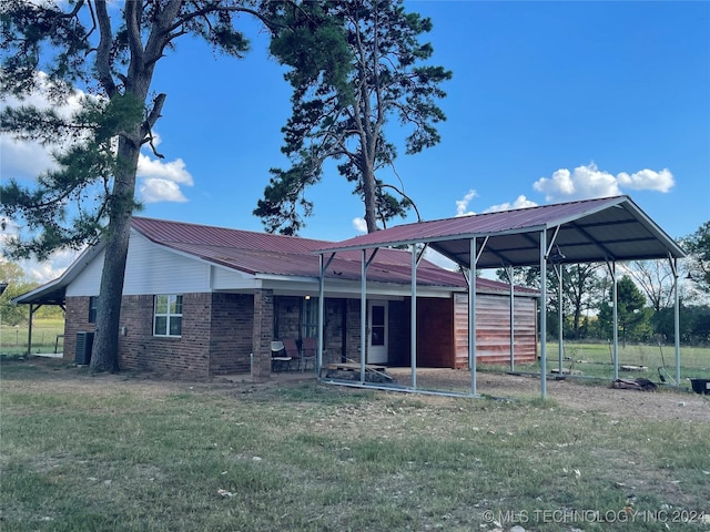 595 N 4340th Rd, Fort Towson, OK 74735 - rear view of house featuring brick siding, a lawn, metal roof, a carport, and central air condition unit