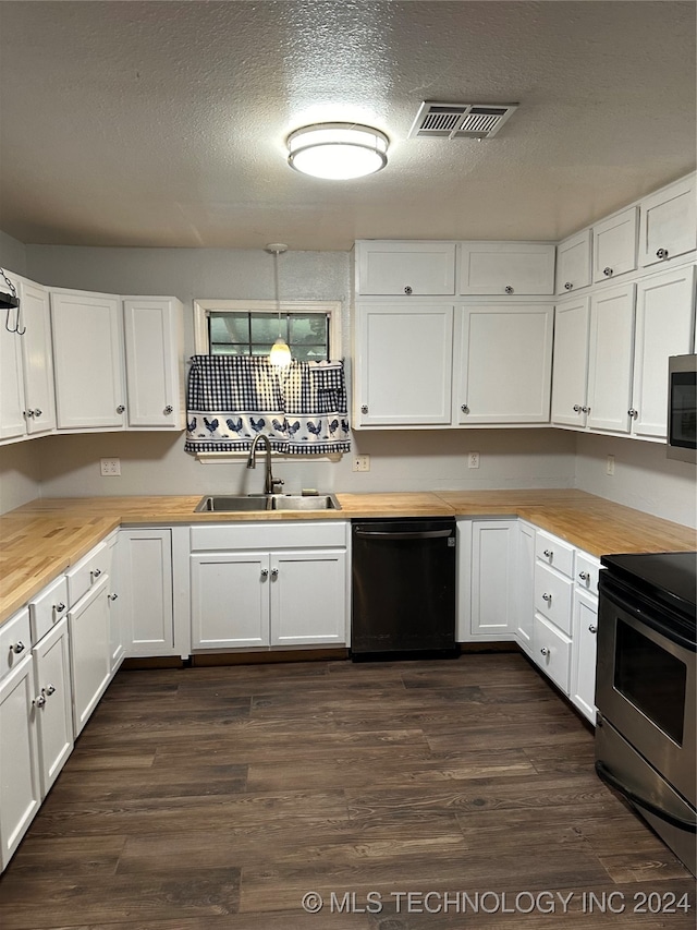 kitchen featuring butcher block counters, white cabinets, sink, and pendant lighting