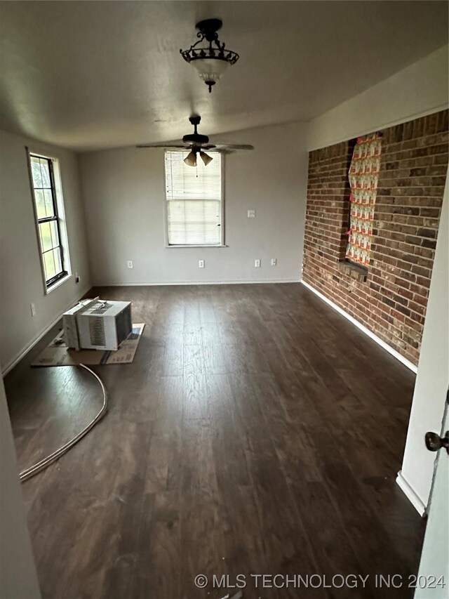 595 N 4340th Rd, Fort Towson, OK 74735 - unfurnished living room with a ceiling fan, wood finished floors, baseboards, brick wall, and an AC wall unit