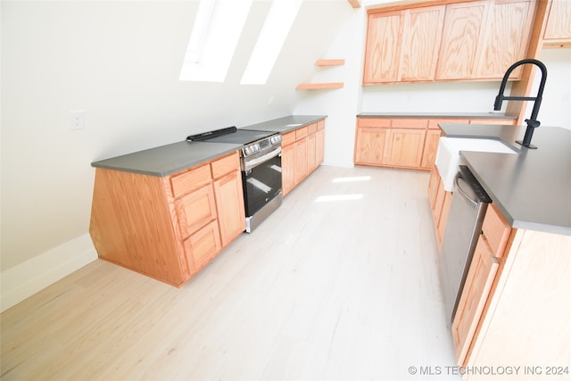 kitchen featuring appliances with stainless steel finishes, light hardwood / wood-style floors, light brown cabinets, and a skylight