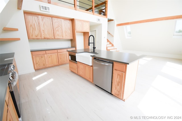 kitchen with light brown cabinets, sink, a center island with sink, light hardwood / wood-style flooring, and appliances with stainless steel finishes