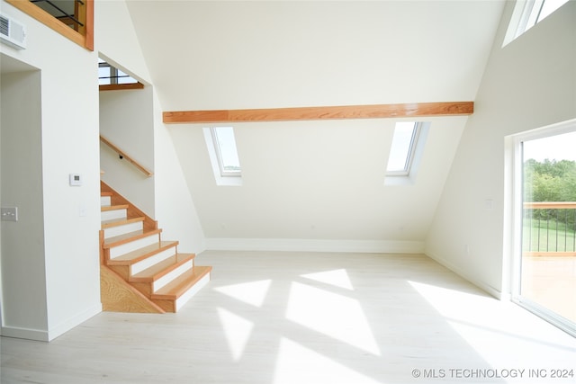 interior space featuring high vaulted ceiling, light wood-type flooring, and a skylight