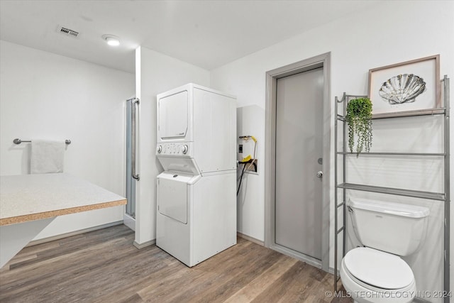 bathroom featuring hardwood / wood-style floors, toilet, and stacked washer / dryer