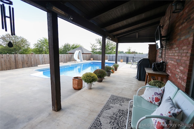 view of swimming pool with a water slide and a patio area