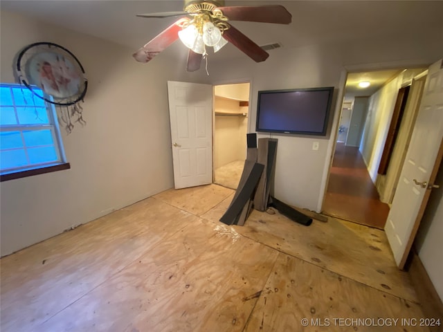 unfurnished bedroom with a spacious closet, ceiling fan, and a closet