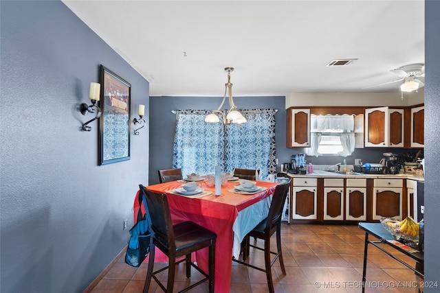 tiled dining room with sink and ceiling fan with notable chandelier